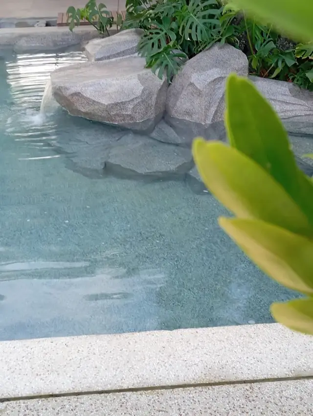 Queda de água em pedras artificiais na borda da piscina