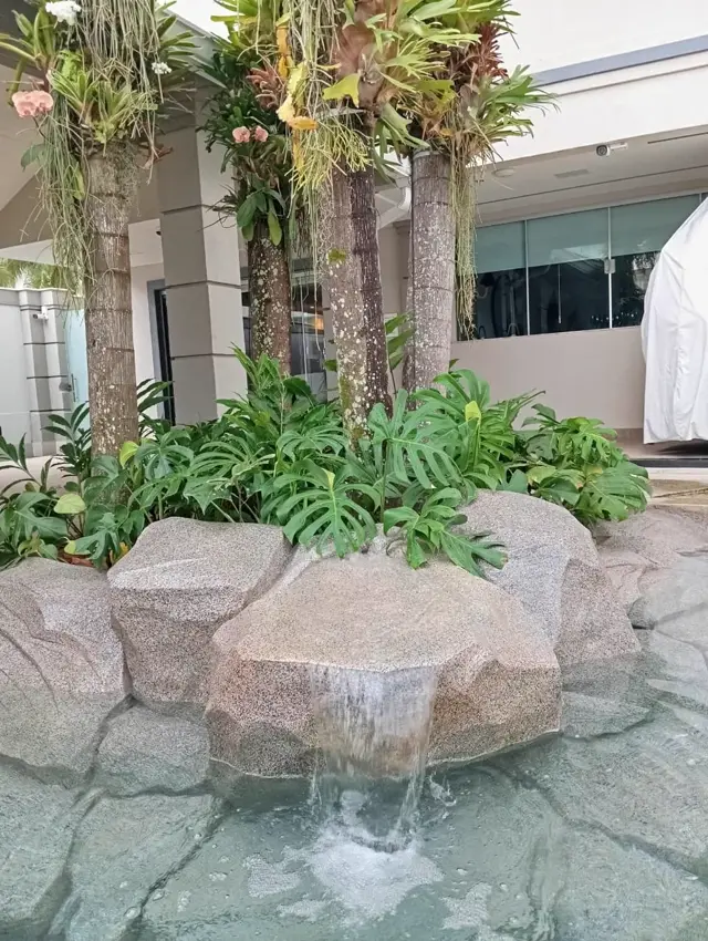 Cascata em ilha de pedra artificial com palmeiras e orquídeas